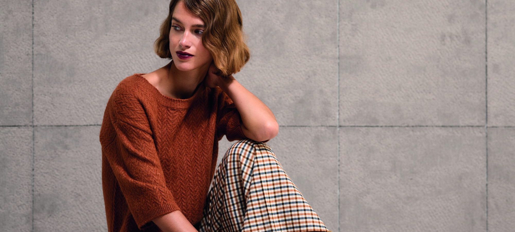 Model in terracotta trui met geruite broek uit de najaarscollectie