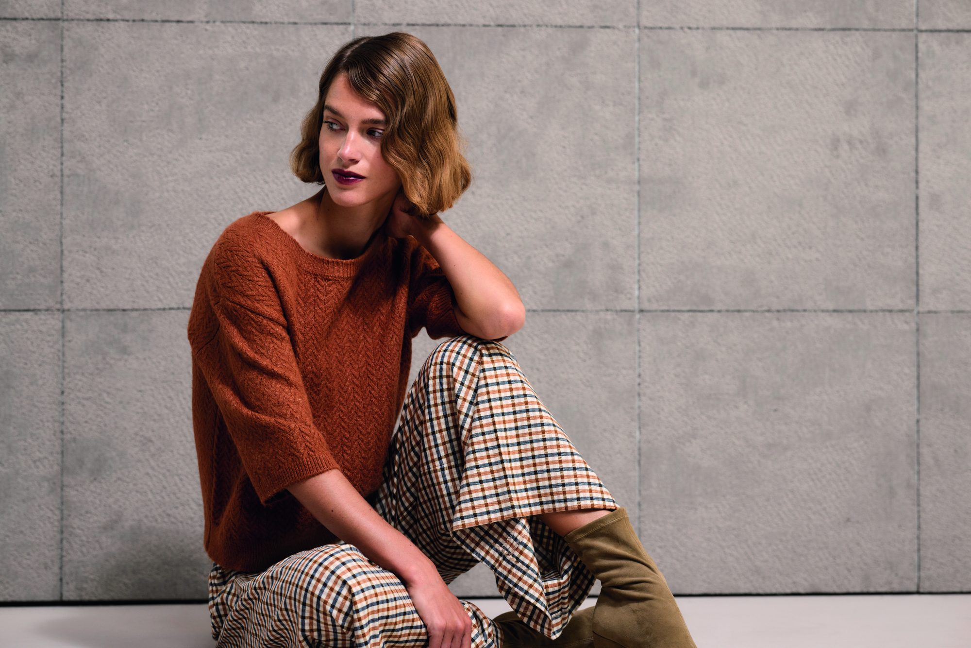 Model in terracotta trui met geruite broek, najaarscollectie